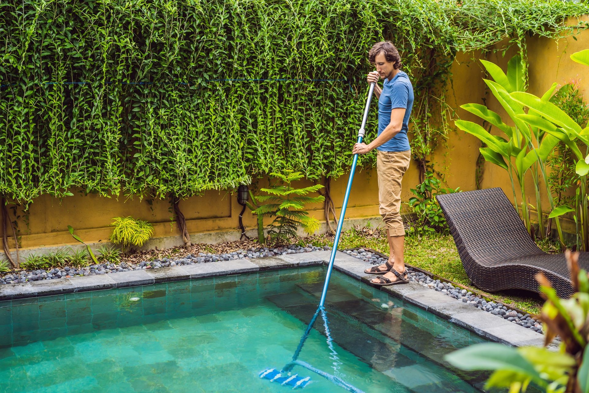 Cleaner of the swimming pool . Man in a blue shirt with cleaning equipment for swimming pools. Pool cleaning services