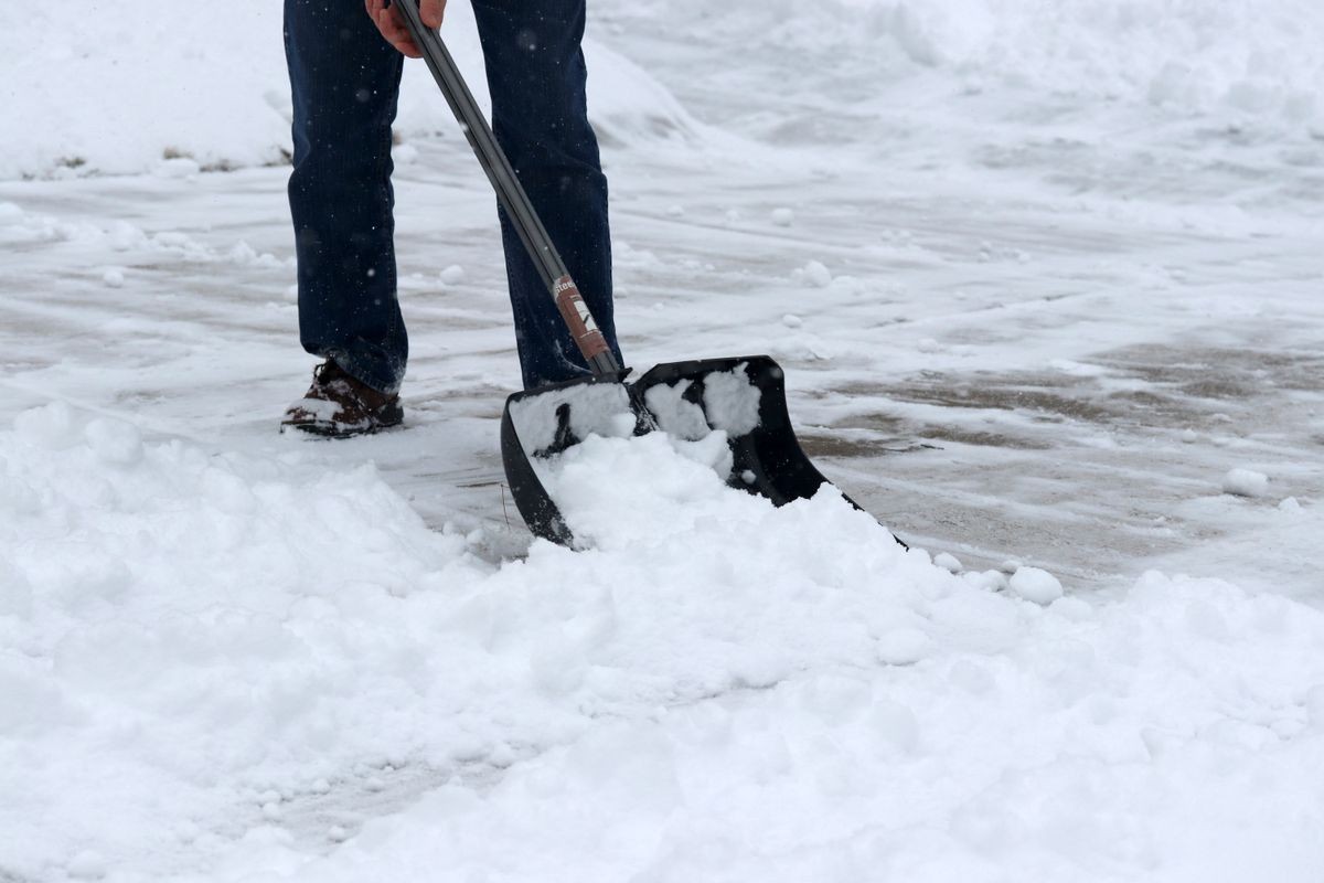 Winter snowy day background. Man shoveling snow on driveway during a heavy snowfall. Close up composition.