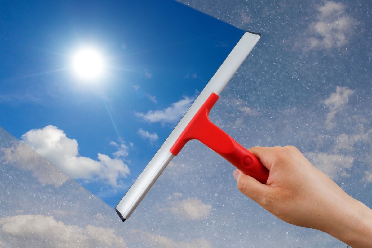 Cleaning window with rubber squeegee and cleaning the sky. Concept and background window cleaning.